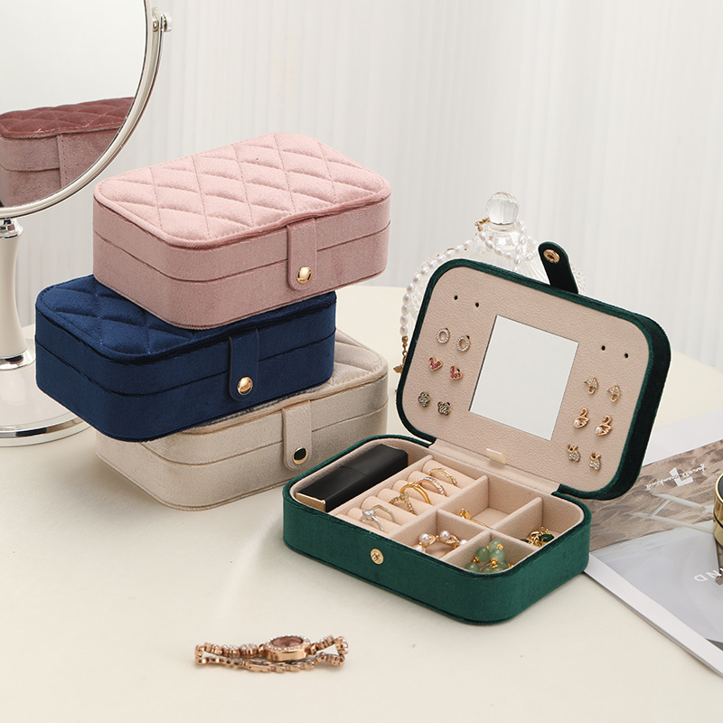 Pink, navy, beige and green jewelry organizers, including an open case with compartments and a mirror
